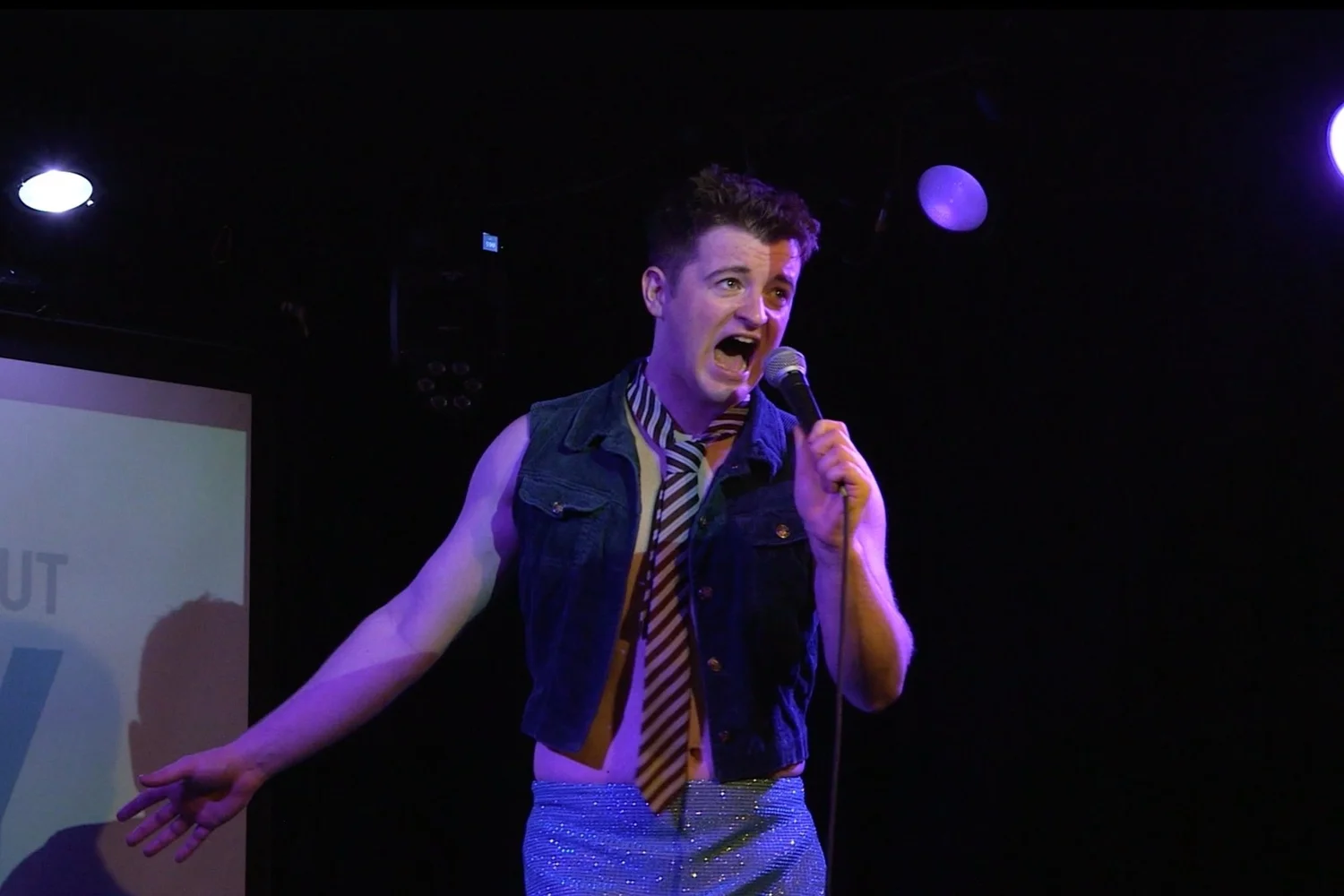 actor standing on stage with colourful background