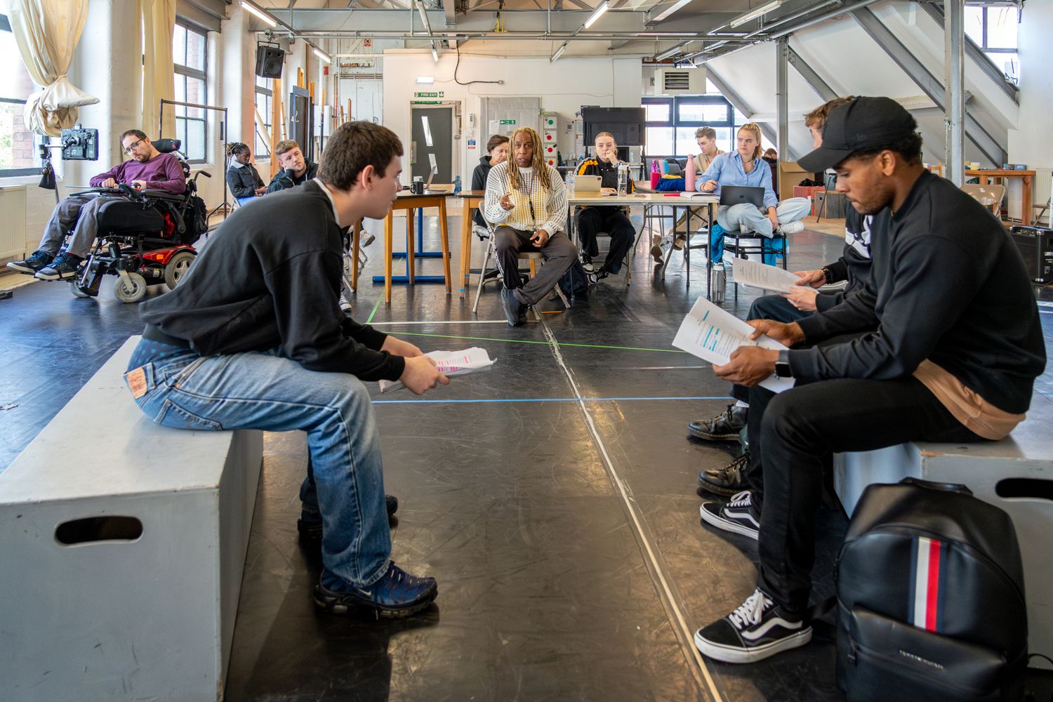 actors with scripts and director in rehearsal space